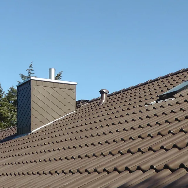 Steildach mit braunen Dachziegeln und Schornsteinverkleidung aus Schiefer – Bauklempnerei und Dacharbeiten in Ratzeburg